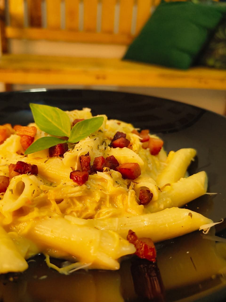 Penne com molho cremoso e manjericão em prato preto